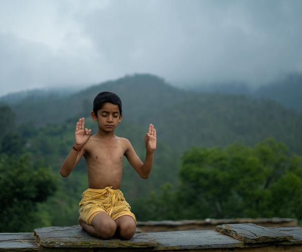 A child balancing on one leg in a tree pose with a look of concentration.