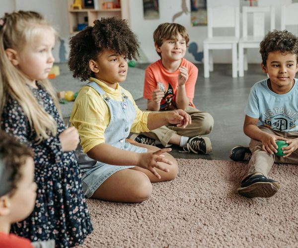 Group of kids sitting in a circle and smiling during a yoga class.
